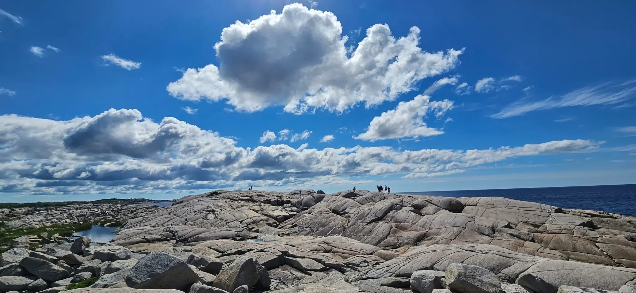 Granite coastline at Peggy's Cove beneath a wide blue sky on Nova Scotia's Atlantic shore